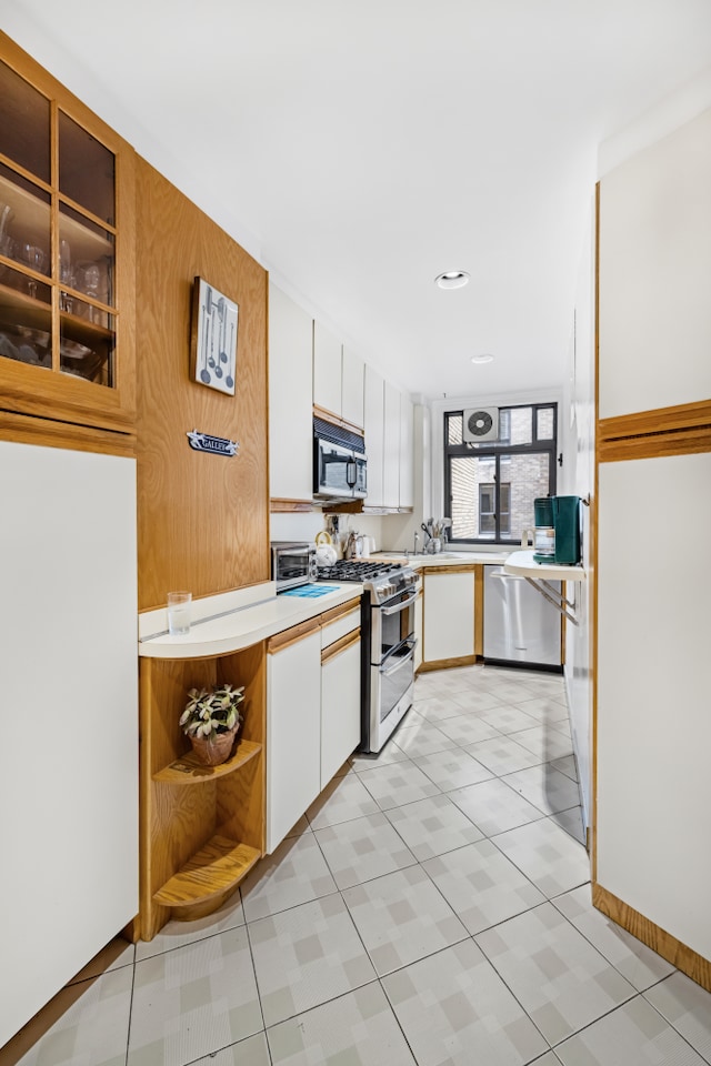 kitchen with appliances with stainless steel finishes, light countertops, white cabinetry, and open shelves