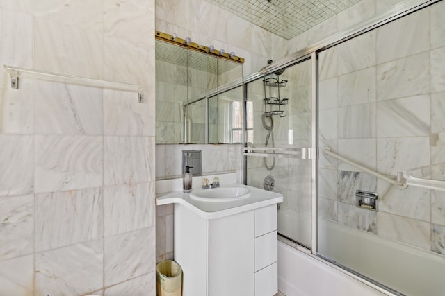 full bath with tile walls, combined bath / shower with glass door, and vanity