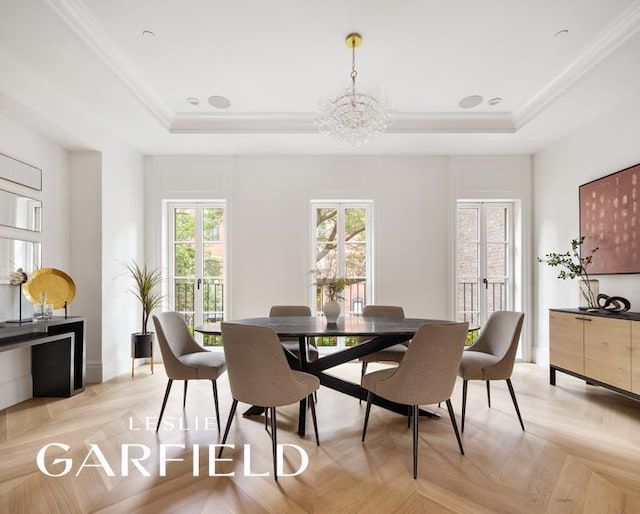 dining space featuring crown molding, light parquet flooring, a tray ceiling, and an inviting chandelier