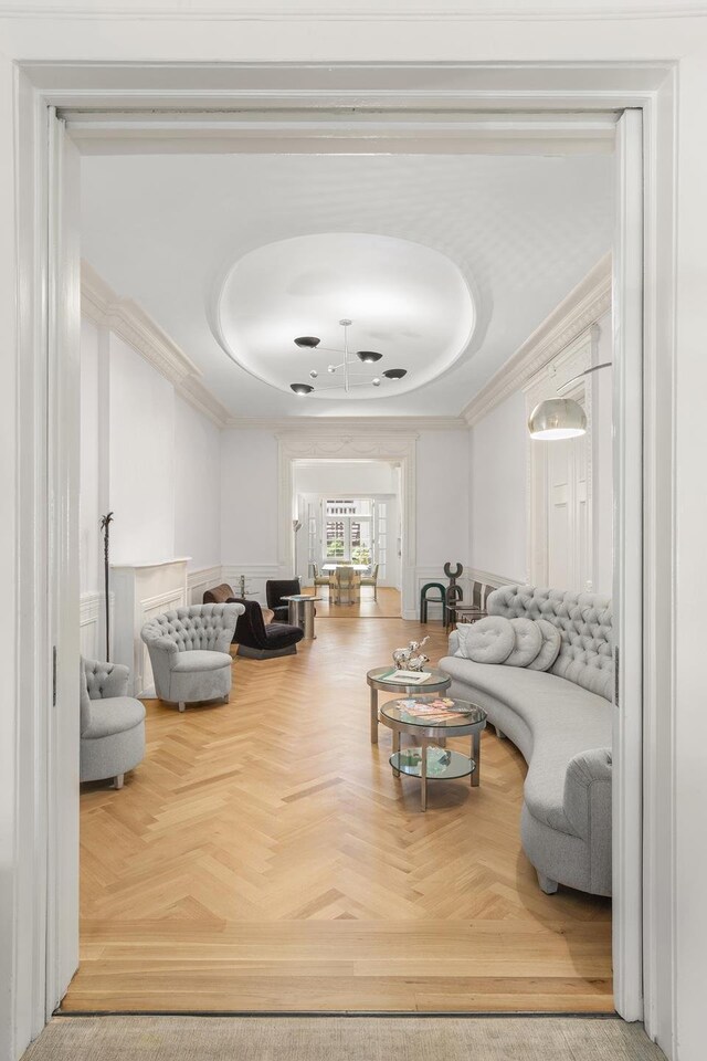 living room featuring parquet flooring, ornamental molding, and a raised ceiling