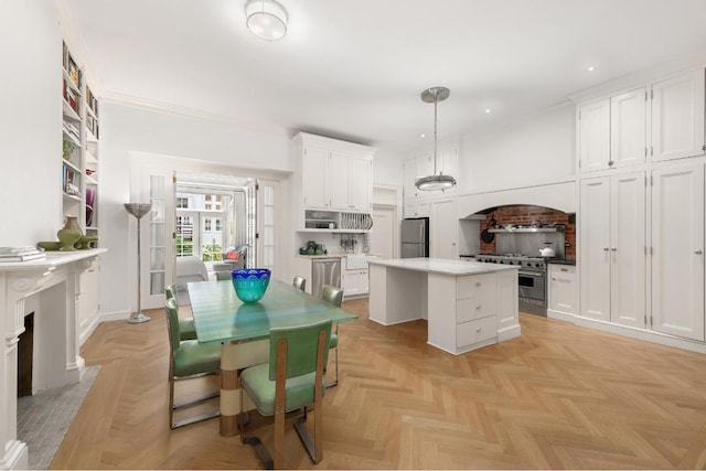 kitchen with appliances with stainless steel finishes, a center island, white cabinets, and decorative light fixtures