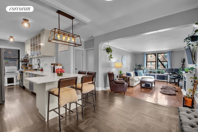 kitchen with a breakfast bar area, tasteful backsplash, ornamental molding, decorative light fixtures, and kitchen peninsula