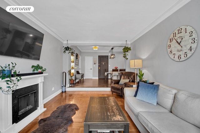 living room with a fireplace, crown molding, baseboards, and wood finished floors