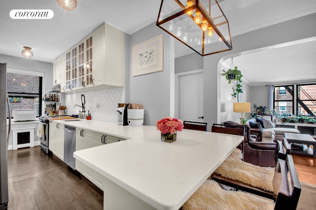 kitchen with visible vents, light countertops, stainless steel dishwasher, glass insert cabinets, and pendant lighting