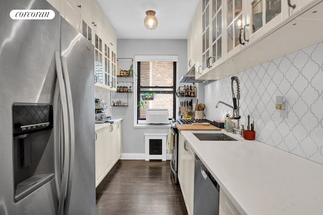 kitchen with white cabinets, glass insert cabinets, dark wood-type flooring, stainless steel appliances, and light countertops