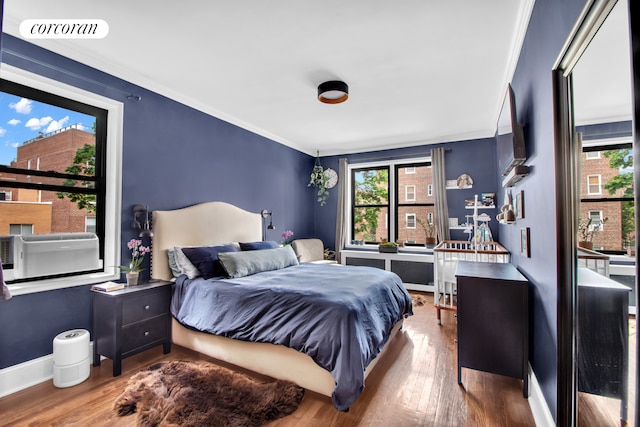 bedroom with baseboards, wood finished floors, visible vents, and crown molding