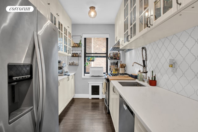 kitchen featuring dark hardwood / wood-style floors, white cabinetry, sink, backsplash, and stainless steel appliances