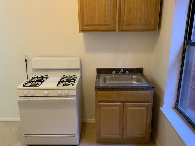 546 W 156th St Unit 11, New York City, NY 10032 - kitchen featuring dark countertops, baseboards, white range with gas stovetop, and a sink