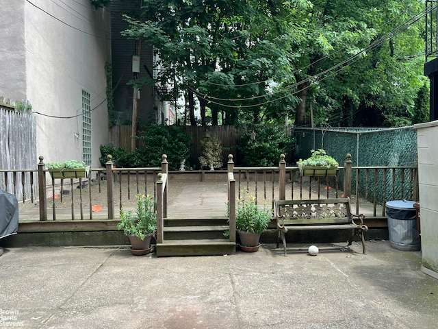 exterior space featuring fence, a wooden deck, and a patio