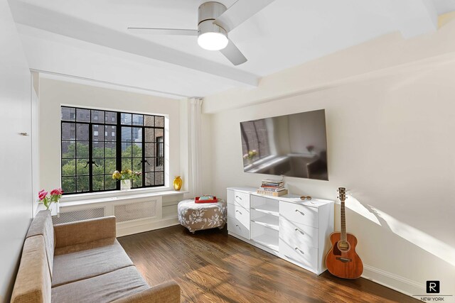 living area featuring beamed ceiling, dark hardwood / wood-style floors, and ceiling fan