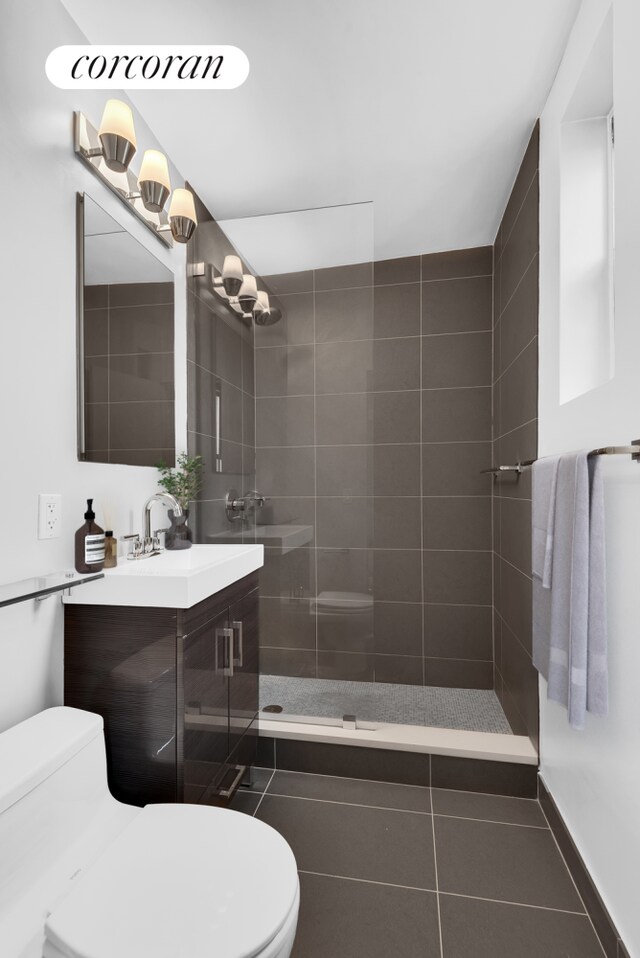 bathroom with tile patterned floors, vanity, toilet, and a tile shower