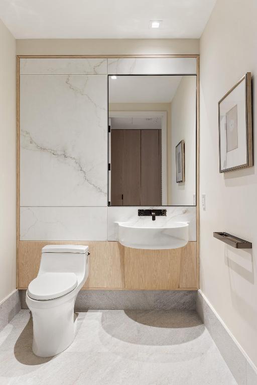 half bathroom with toilet, a sink, and tile patterned floors