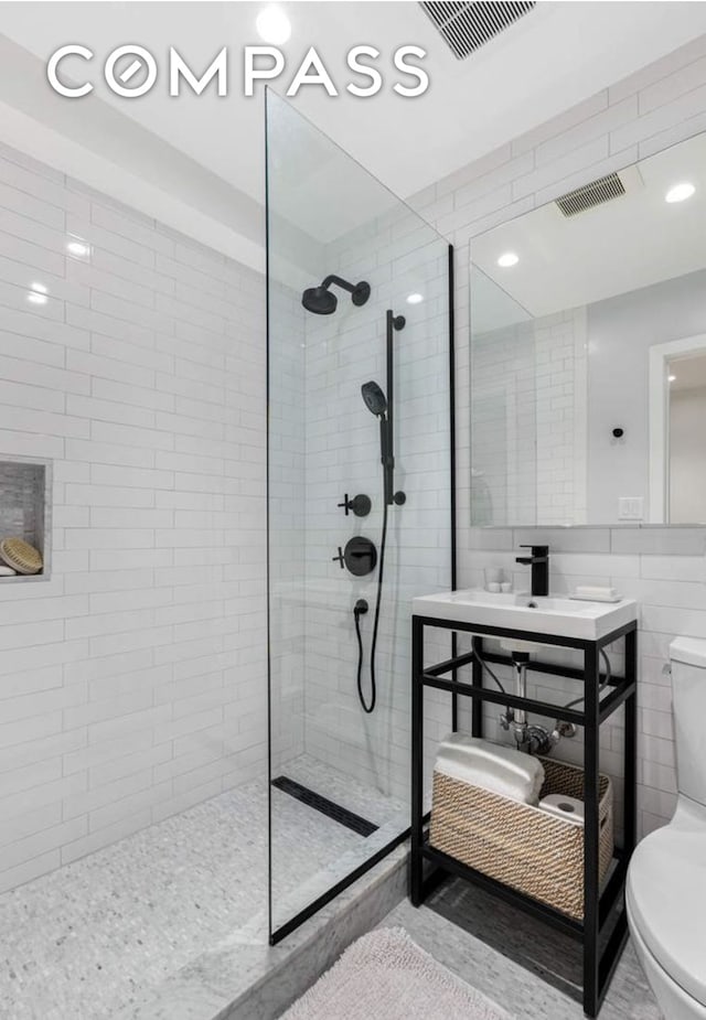 bathroom with toilet, visible vents, walk in shower, and tile walls