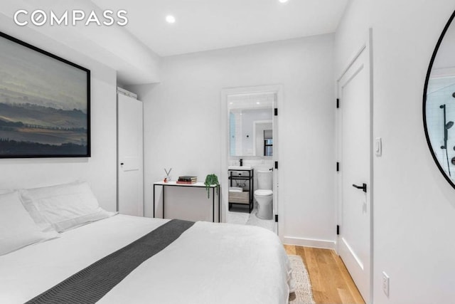 bedroom with a sink, recessed lighting, ensuite bath, and light wood-style floors