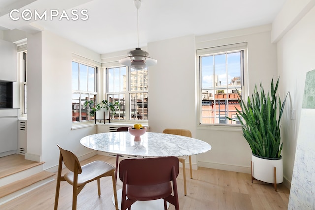 dining space with light wood-type flooring and baseboards