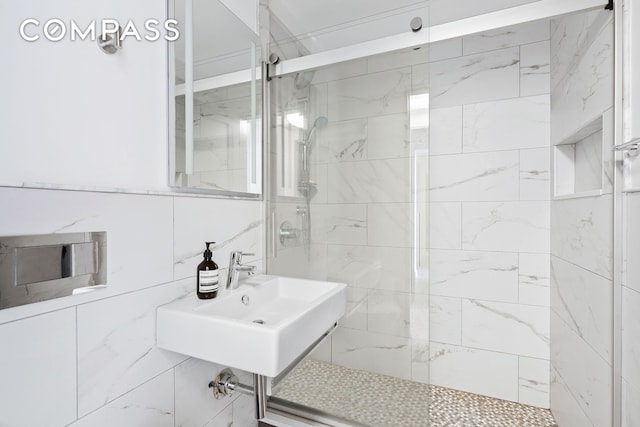 full bathroom featuring a shower stall, tile walls, and a sink