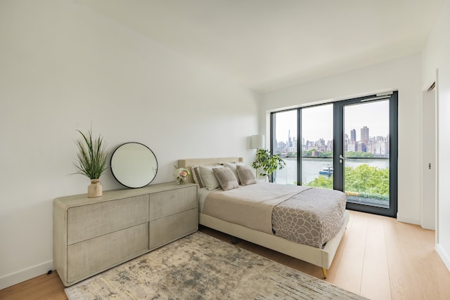 30-05 Vernon Blvd Unit 2-B, New York City, NY 11102 - bedroom featuring baseboards, access to exterior, a view of city, light wood-style floors, and a water view