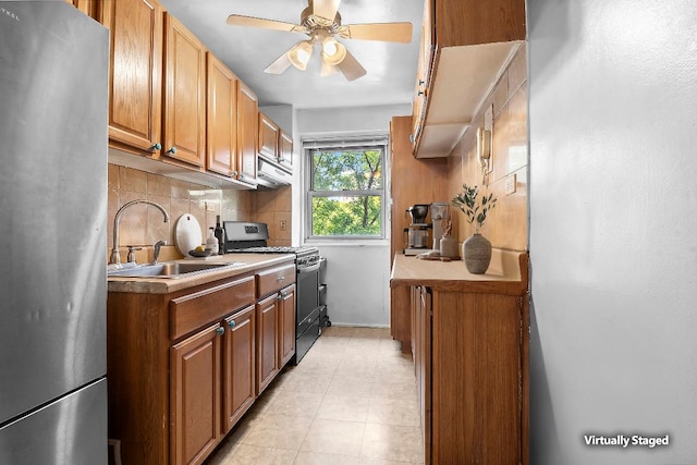 kitchen with appliances with stainless steel finishes, sink, decorative backsplash, light tile patterned floors, and ceiling fan