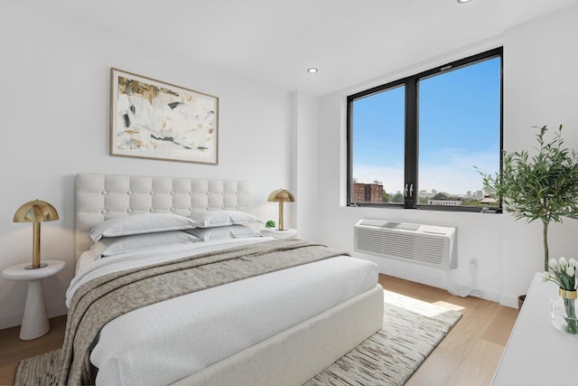 bedroom featuring a wall unit AC and light wood-type flooring