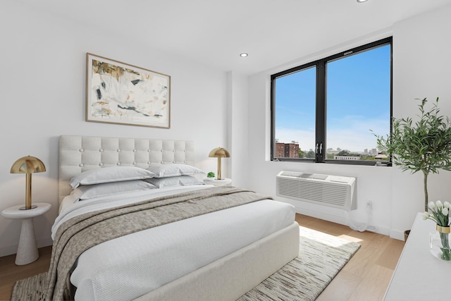 bedroom featuring an AC wall unit, baseboards, recessed lighting, and wood finished floors