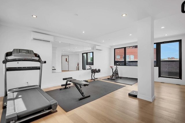 exercise room featuring an AC wall unit, baseboards, recessed lighting, and wood finished floors