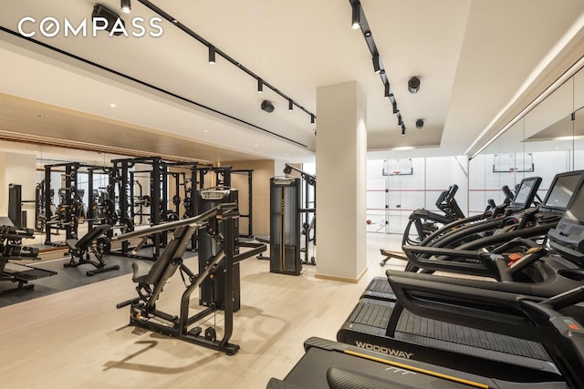 gym with light wood-style floors and track lighting