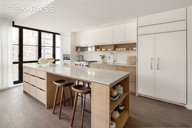 kitchen with white cabinets, a kitchen island, light countertops, open shelves, and a sink