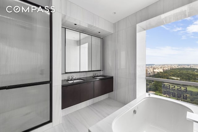 bathroom with vanity, tile walls, and a tub to relax in