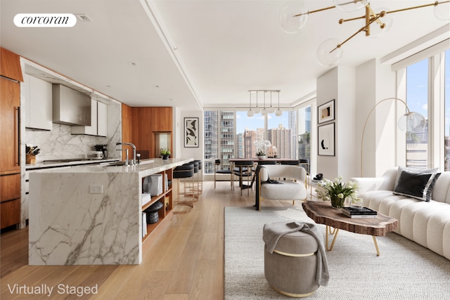 living room featuring expansive windows, a healthy amount of sunlight, light hardwood / wood-style floors, and a notable chandelier