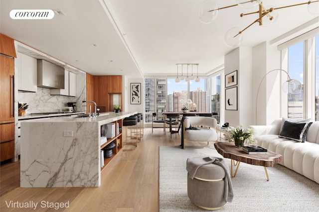 living area with plenty of natural light, light wood-style floors, a view of skyline, expansive windows, and a chandelier