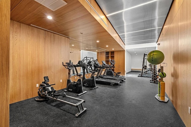 exercise room featuring wooden ceiling, wooden walls, and recessed lighting