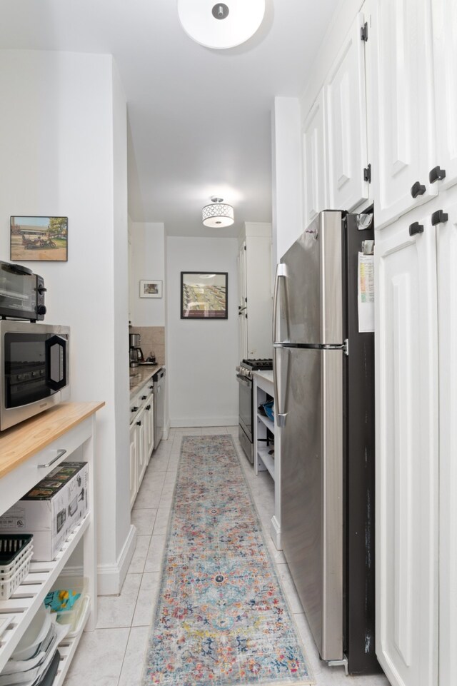 kitchen featuring white cabinets, appliances with stainless steel finishes, and light tile patterned flooring