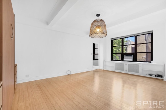 235 E 22nd St Unit 4M, New York City, NY 10010 - empty room featuring wood finished floors, beam ceiling, cooling unit, baseboards, and radiator heating unit