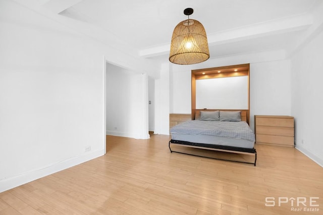 235 E 22nd St Unit 4M, New York City, NY 10010 - bedroom featuring beamed ceiling, wood finished floors, and baseboards