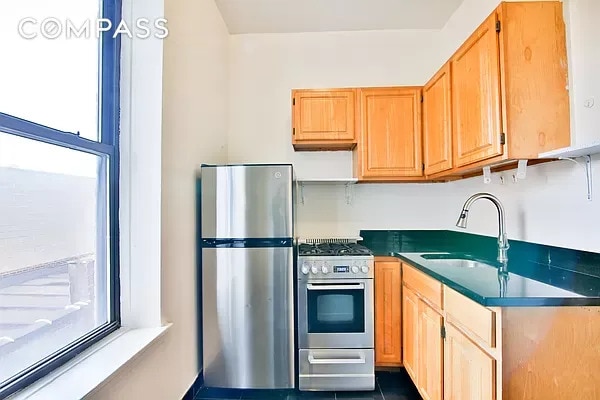 kitchen featuring dark countertops, dark tile patterned flooring, appliances with stainless steel finishes, and a sink