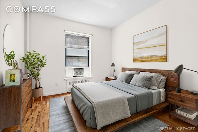 bedroom featuring hardwood / wood-style flooring, radiator, and cooling unit