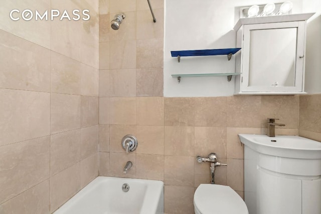 full bathroom featuring vanity, toilet, tiled shower / bath combo, and tile walls