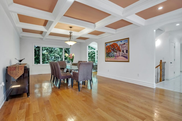 dining room with baseboards, coffered ceiling, light wood finished floors, beam ceiling, and arched walkways