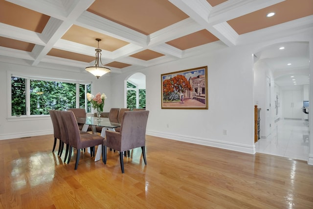 dining room featuring arched walkways, beamed ceiling, and light wood-type flooring