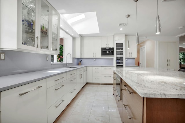 kitchen with visible vents, light tile patterned floors, a skylight, a large island, and a sink