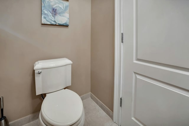 bathroom with baseboards, toilet, and tile patterned flooring