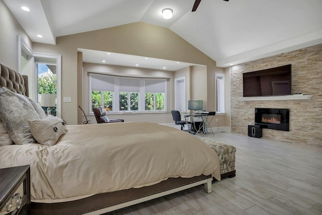 bedroom featuring recessed lighting, lofted ceiling, a stone fireplace, and wood finished floors