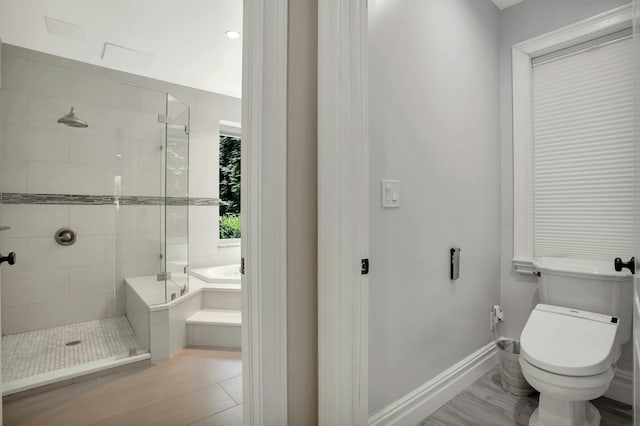 bathroom with a garden tub, toilet, baseboards, and a stall shower