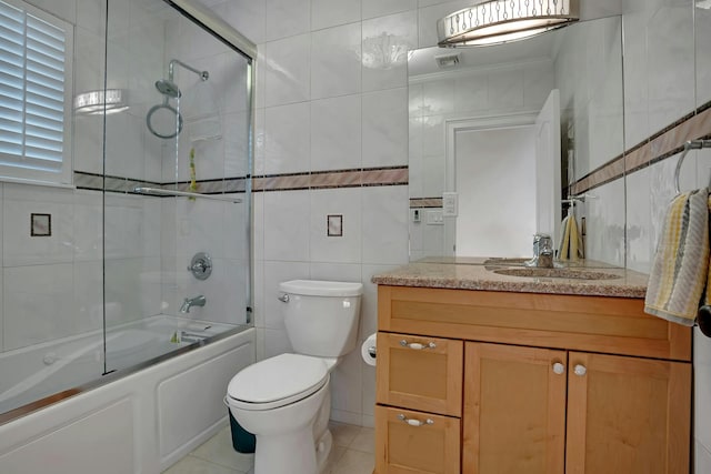 bathroom with tile patterned floors, toilet, combined bath / shower with glass door, tile walls, and vanity