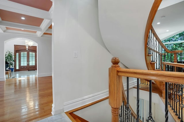 stairway featuring baseboards, coffered ceiling, beam ceiling, arched walkways, and french doors