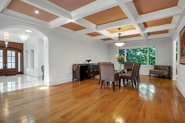 dining space with light wood-style flooring, french doors, arched walkways, and baseboards