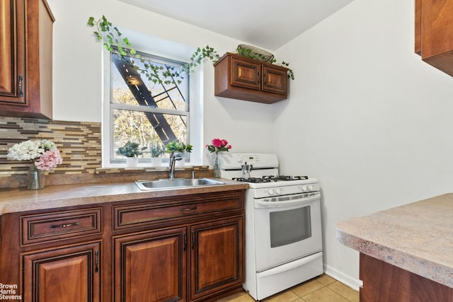 kitchen featuring backsplash, sink, white gas stove, and light tile patterned flooring