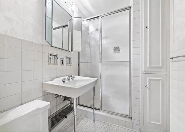 bathroom with tile walls, a shower with door, and toilet