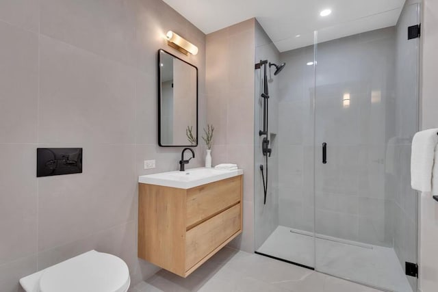 bathroom with vanity, a shower with door, toilet, and tile walls