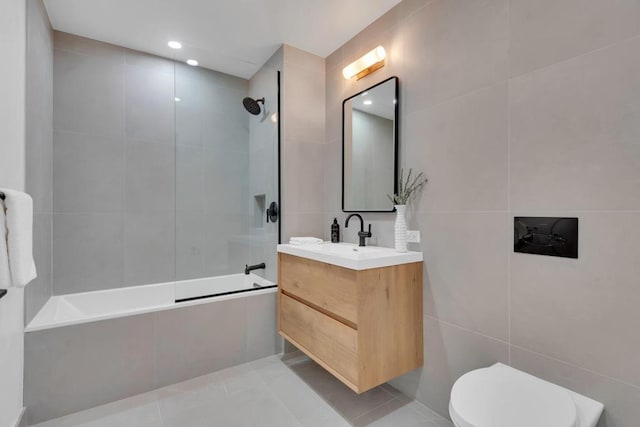 full bathroom featuring tiled shower / bath, tile walls, tile patterned flooring, vanity, and toilet